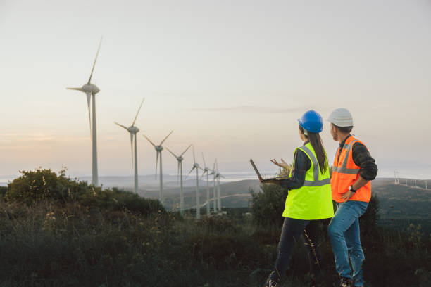 istock Young maintenance engineer team working in wind turbine farm at sunset 1957459069