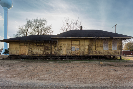 Boarded up train depot left abandoned with vines growing on walls in deep rural Mississippi