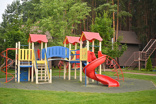 Children at the playground. Focus is on little girl sliding with her arms raised.  