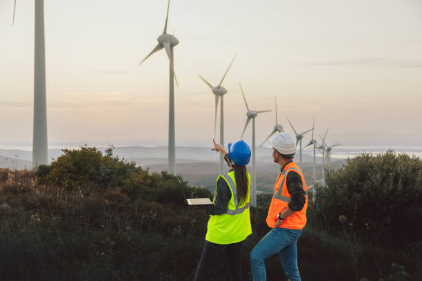 istock Young maintenance engineer team working in wind turbine farm at sunset 1957467557