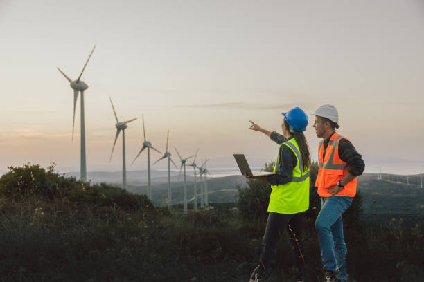 istock Young maintenance engineer team working in wind turbine farm at sunset 1957467559