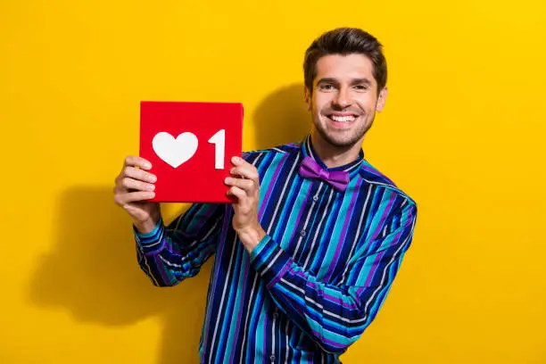 Photo of Portrait of positive cheerful man with bristle wear vintage bow tie demonstrate social media like isolated on yellow color background