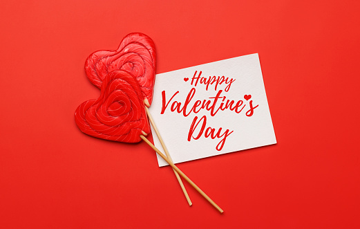 Heart lollipops: Sweet treats on a red backdrop with text space. Flat lay Valentines day card