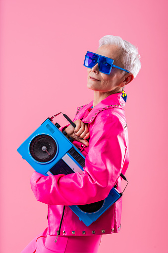 Happy and funny senior old woman wearing fashinable clothing on colorful background- Modern cool fancy grandmother portrait, concepts about elderly and older people