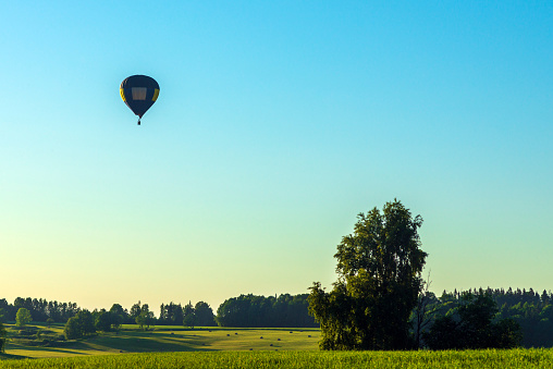 One silhouette hot air balloon in blue sky landscape background.Hot air balloon over the green field.