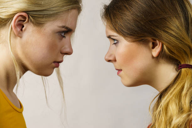 Two young women looking serious at each other. Friendship, difficult relationship.