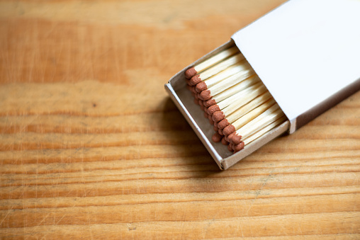 Wooden safety matchsticks stacked in cardboard matchbox on wooden background.Box of matches.Wooden table.copy space.Open box of matches.closeup.