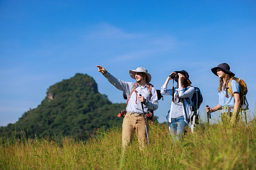 family trekking backpacker pointing finger and using binoculars to see view,