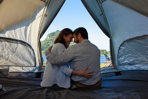 caucasian couple sitting inside a tent on camping trip, expression of love concept,