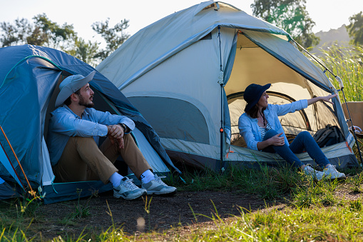 causasian men and woman sitting inside tent and pointing finger, camping trip