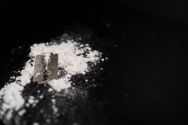 istock Razor Blade on drug powder on reflection black background.Copy space. 1957567327