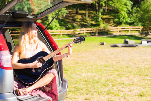 istock Hippie woman playing guitar in van car 1957568981