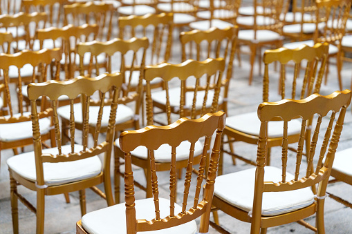 Golden Chiavari chairs add an elegant touch to an outdoor courtyard wedding, enhancing the atmosphere with their luxurious and stylish design.