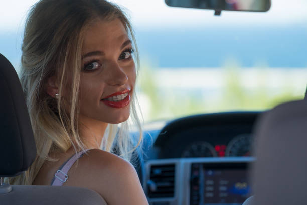 Young driver, pretty blonde woman behind steering wheel. Female riding using car, traveling, going on vacations.