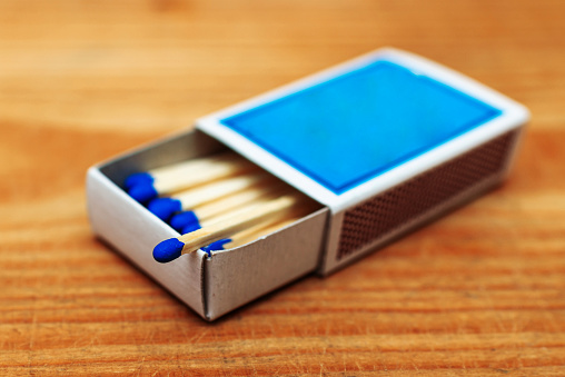 Matches in box on wooden background. Closeup shot. Matchsticks in open match-box flat lay.Matches in open match-box on a carton underlay.Selective focus.Copy space.
