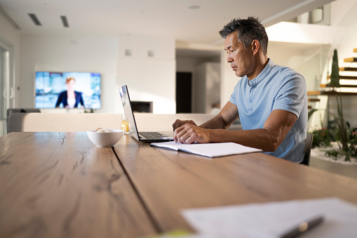 Businessman talking on video conference call on laptop while sitting at home.