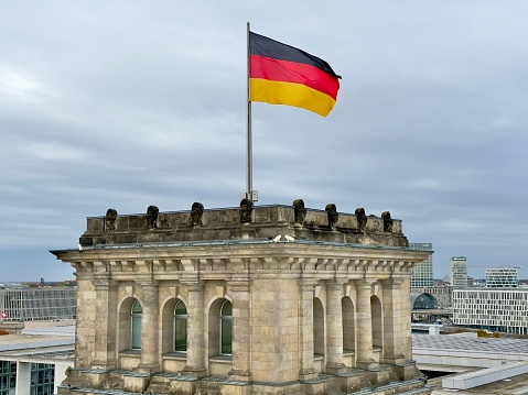 Berlin, Germany - November 9, 2023: The German flag flying from the Reichstag Parliament building in Berlin against a grey sky background.