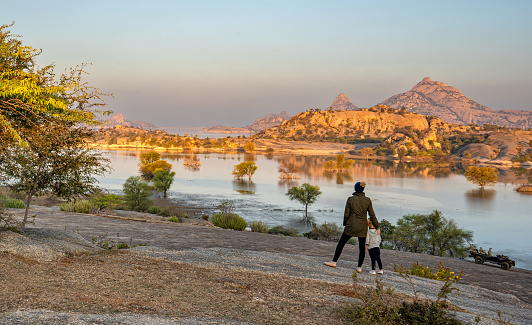 Mother and daughter enjoying a vibrant sunrise over the dramatic boulder covered landscape in the Jawai region of Rajasthan, India Asia.