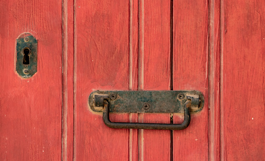 Red wooden door with door handle and lock