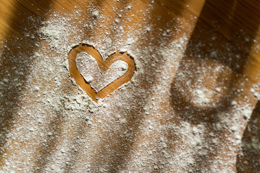 High angle view of a heart shape on flour at the table
