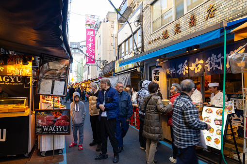 Tokyio, Japan. January 2024. people strolling among the food stalls at the Tsukiji Outer Market in the city center