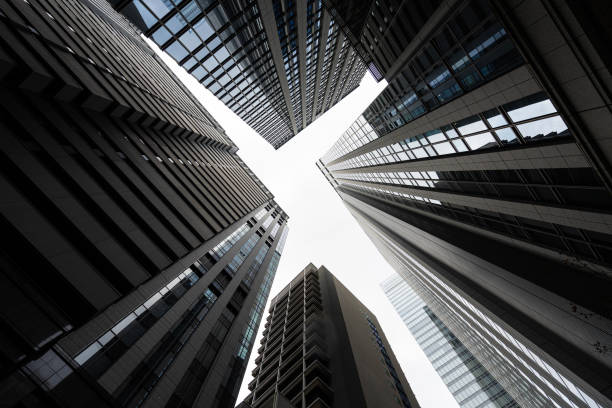 A stunning upward shot of tall skyscrapers reaching towards a partly cloudy sky, showcasing a sense of urban scale and modern architecture during midday. NYC, Manhattan
