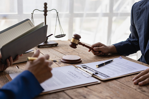 Attorneys work with clients in the office and speak with clients to discuss legal details. Close-up of a judge with a gavel and a professional lawyer discussing a legal case.