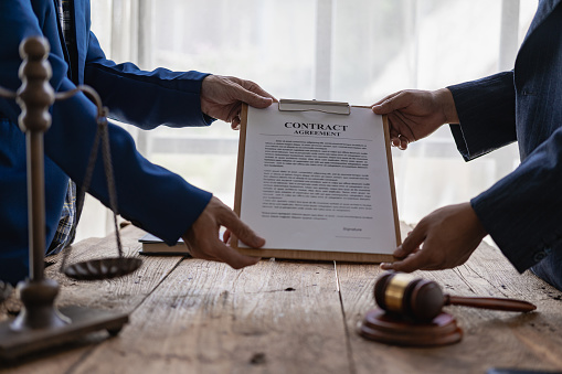 Attorneys work with clients in the office and speak with clients to discuss legal details. Close-up of a judge with a gavel and a professional lawyer discussing a legal case.