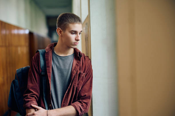 istock Thoughtful high school student looking through the window in a hallway. 1957772064