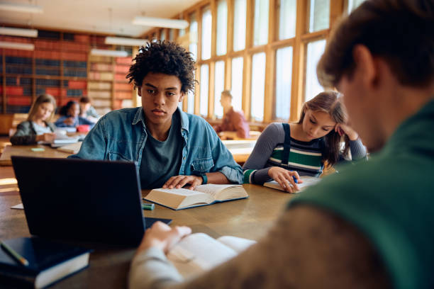 istock Black student and his friends learning in library at high school. 1957775230
