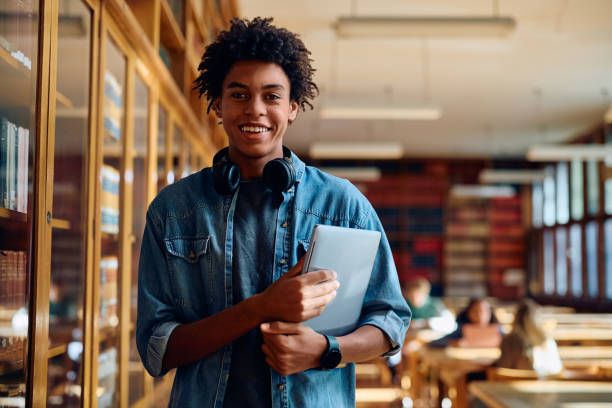 istock Portrait of happy black student at high school library looking at camera. 1957777346