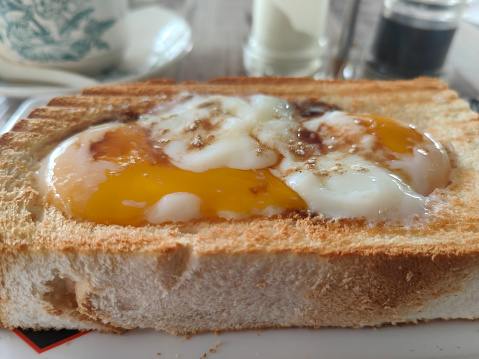 Toasted bread topped with half boiled eggs complete with a cup of coffee