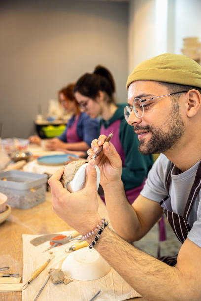 istock Group of people working in pottery studio workshp making bowl from clay. 1957842921