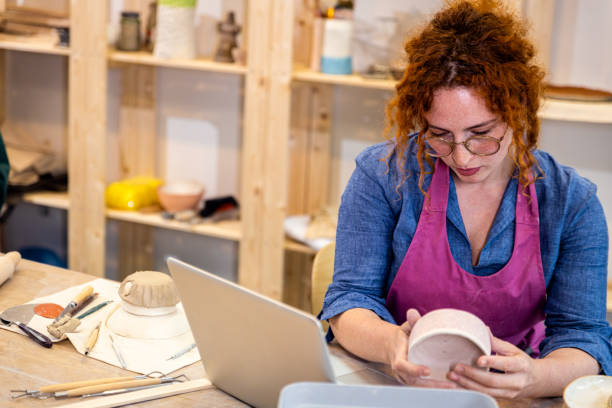 istock Female business owner using laptop in pottery studio workshop. 1957842924