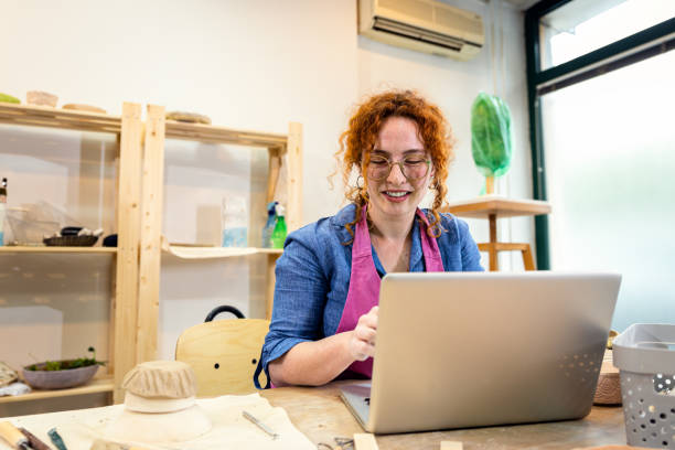 istock Female business owner using laptop in pottery studio workshop. 1957843433