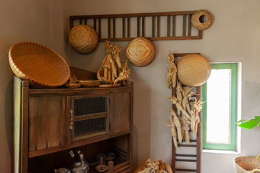 Interior of Vietnamese kitchen with old wooden cabinet, shelf, ladder, rattan basket, dried corn