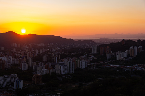 panoramic cityscape at the early morning sunrise over mountain ridge in the city of Valencia, Venezuela. Valencia or Tacarigua lake in the background.