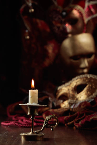 istock Burning candle in an old brass candlestick and carnival masks. 1957880234