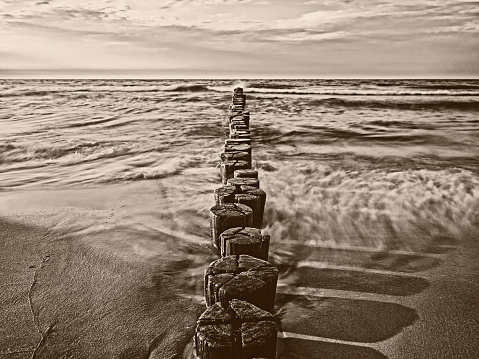 Sepia-toned image of groynes in the Baltic Sea, long exposure.