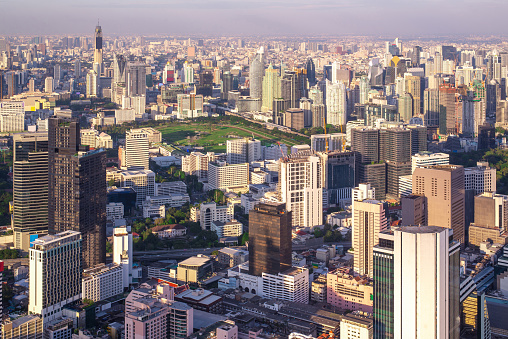 An expansive aerial shot captures a densely populated city's towering skyscrapers and urban layout in soft light.