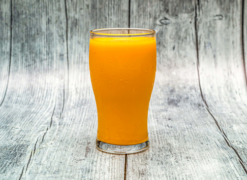 mango lassi served in glass isolated on wooden table top view of indian drink