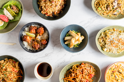 An overhead view captures a table brimming with an array of delectable Asian dishes. The rich and diverse flavors of Asian cuisine. High quality photo