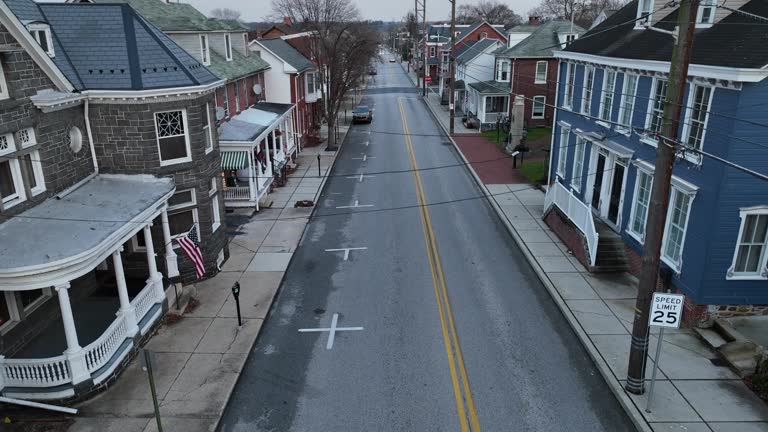 Aerial descending shot of American suburb in winter. Quiet street with old homes. USA flag.