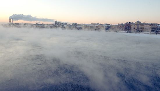 Evening mist above river and industrial pipes with smoke in background, St.Petersburg, Russia