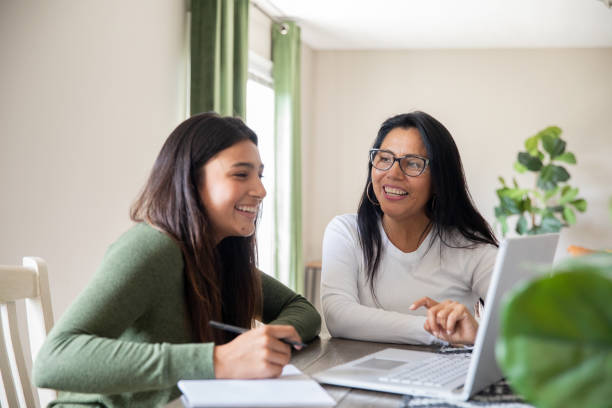 istock Using their home computer, a mother aids her teenage daughter in completing a virtual high school task. 1958009272