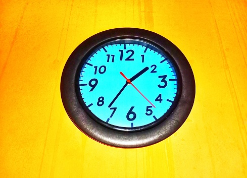 A wall clock with yellow walls
