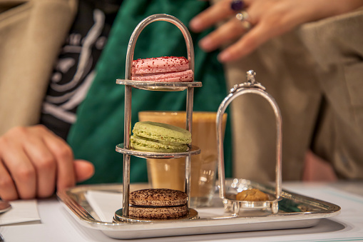 A woman drinking coffee with macarons in a cafe