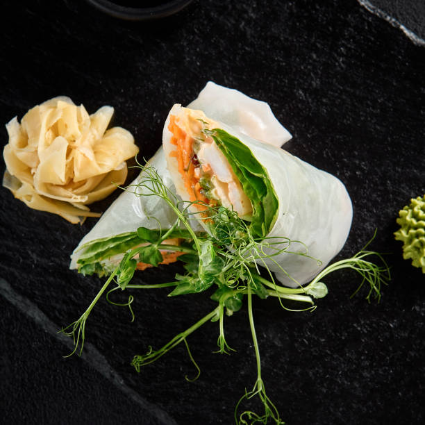 istock Top view of a shrimp spring roll with green pea sprouts on a black slate 1958076114