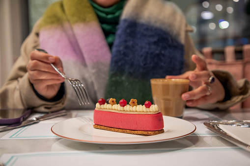 A woman drinking coffee with cake in a cafe