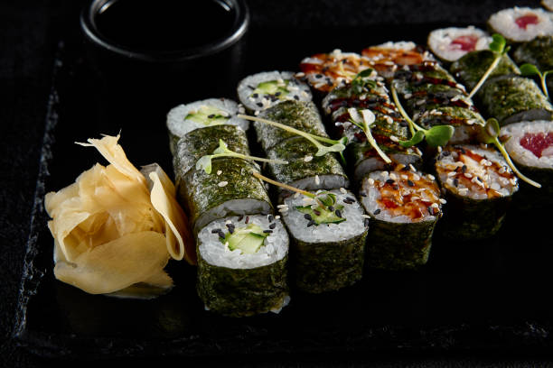 istock Assorted hosomaki sushi set with salmon, tuna, eel, and cucumber on black textured background 1958082421